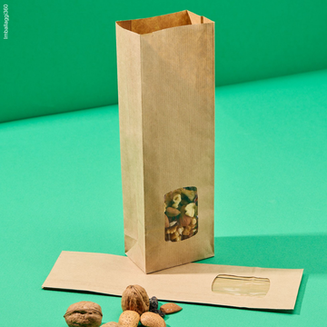 Sacchetto color avana di carta con finestra porta alimenti, mostrato con cibo all'interno ma anche vuoto steso, su sfondo verde
